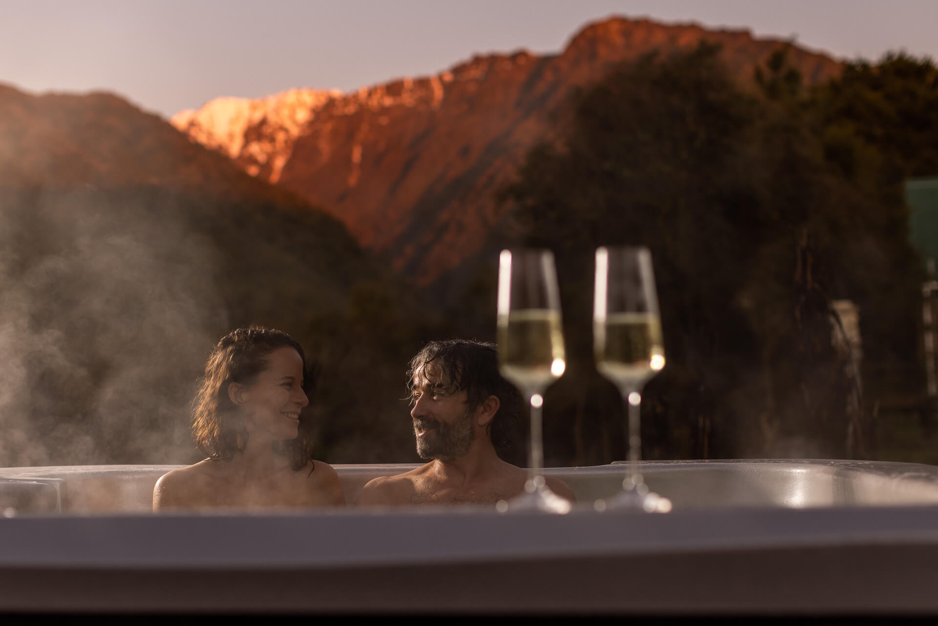 guests enjoying a wine in the spa snowy mountain range behind them