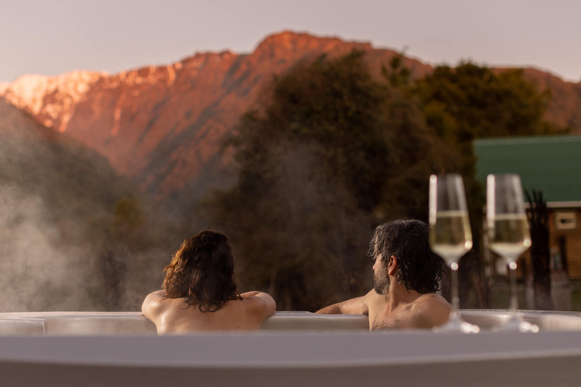 guests enjoying a wine in the spa looking at the snowy mountain range behind them