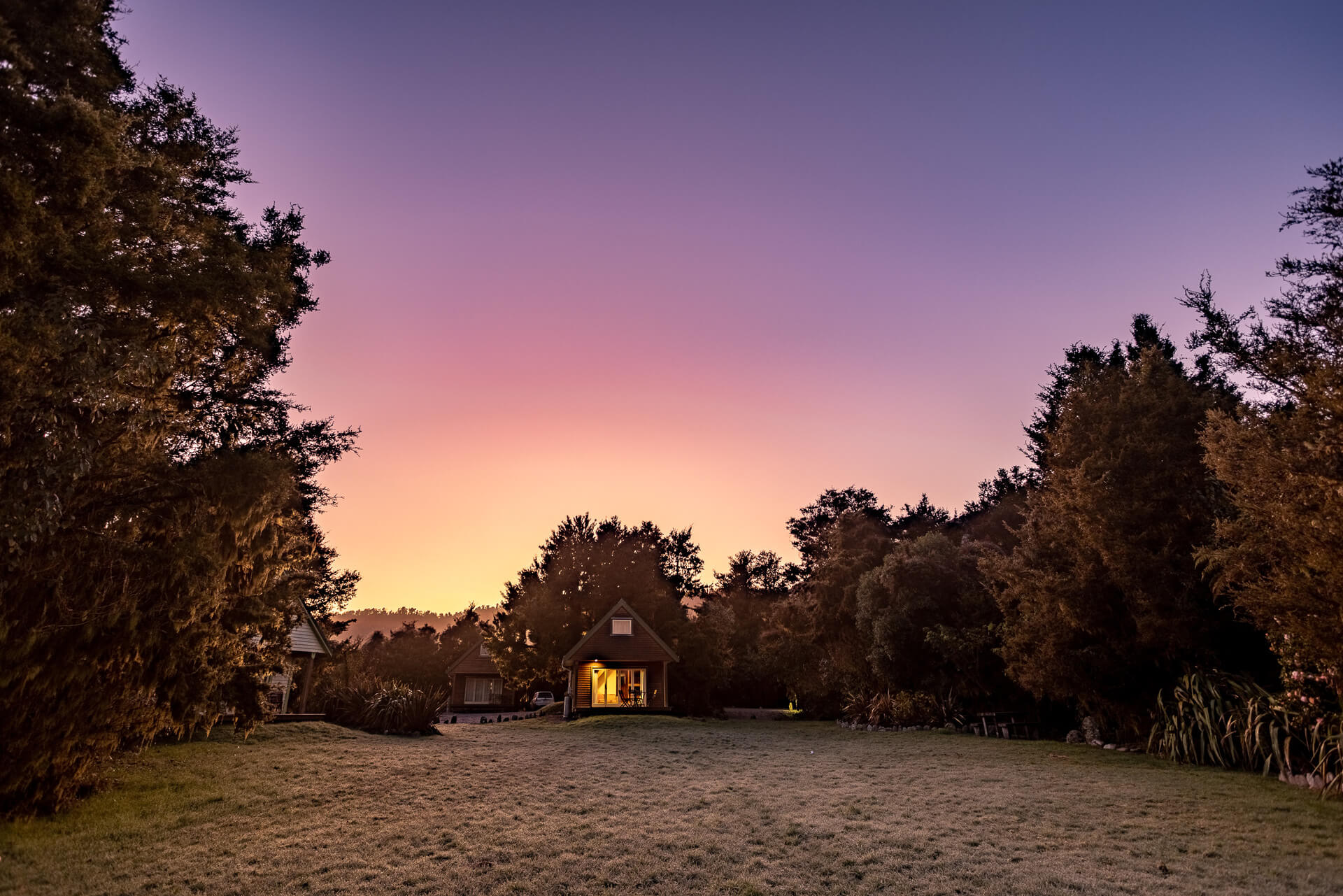 Kahere Retreat chalet and trees with pink skies at sunset